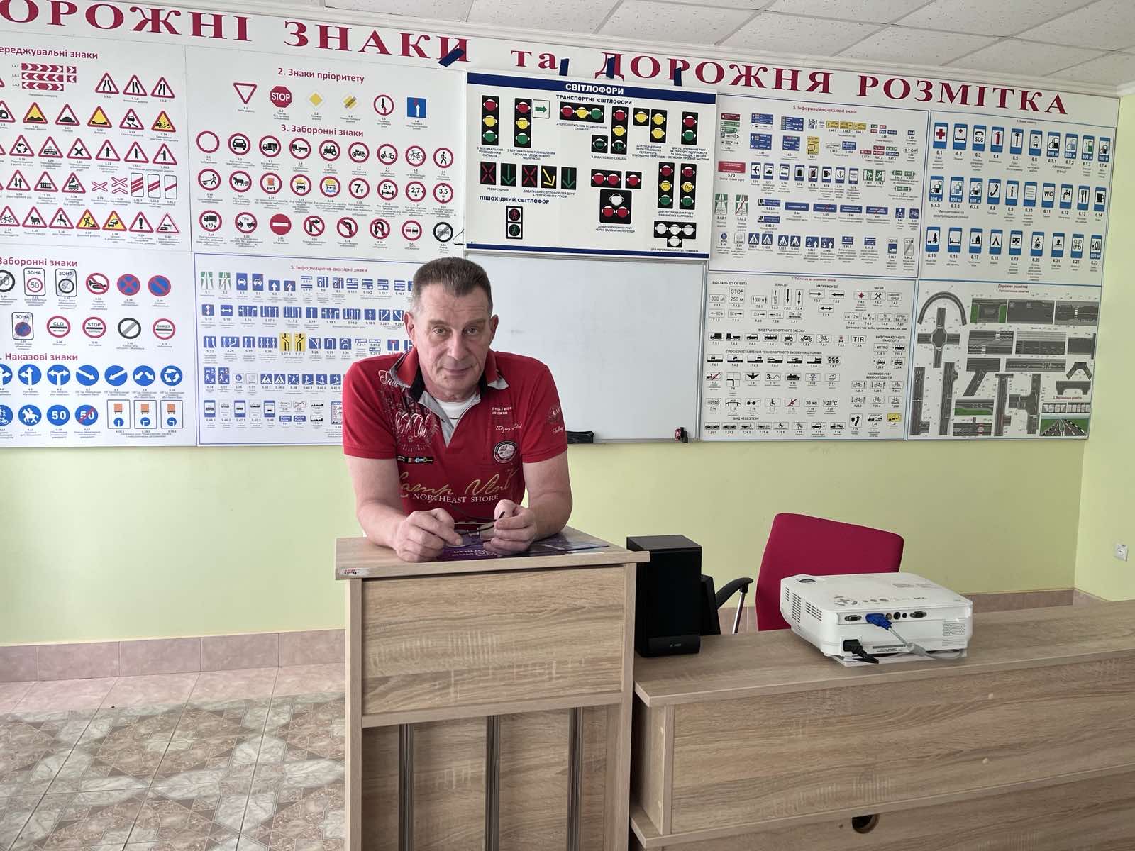 Викладач автошколи в аудиторії з плакатами дорожніх знаків