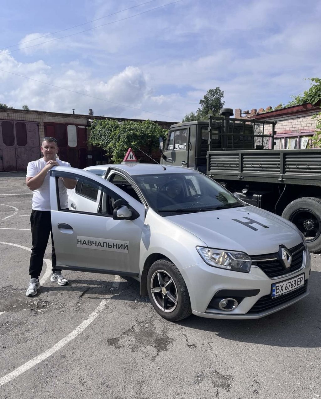 Інструктор з водіння біля навчального Renault Logan на майданчику